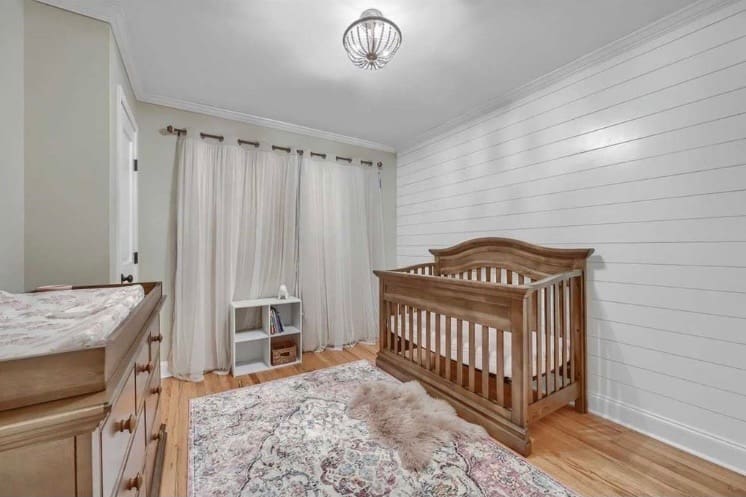 Peaceful neutral-toned baby nursery with wooden crib, soft area rug, and blackout curtains to support healthy sleep routines. Baby Sleep Problems to the rescue with Sara Morse